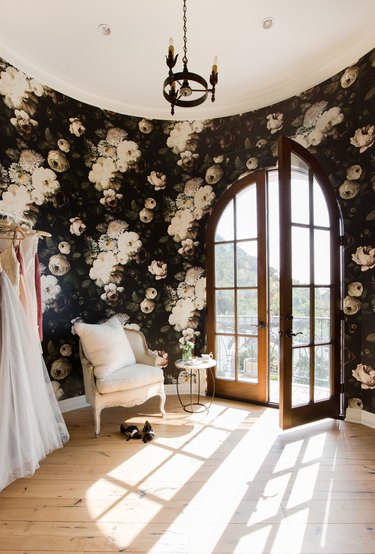 walk-in closet with arch window and statement wallpaper