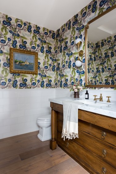 powder room with patterned wallpaper and wood and white vanity