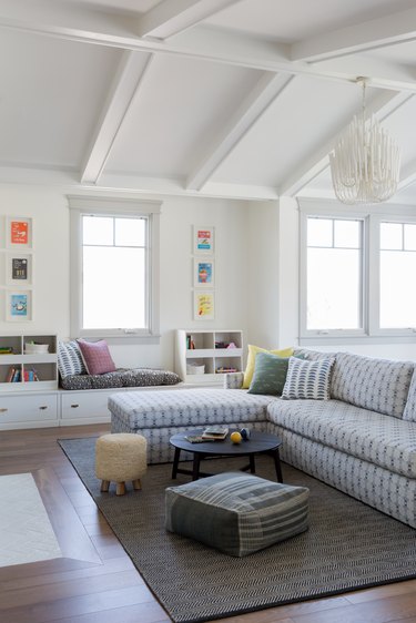 kids playroom with sectional sofa and windows and white ceiling beams