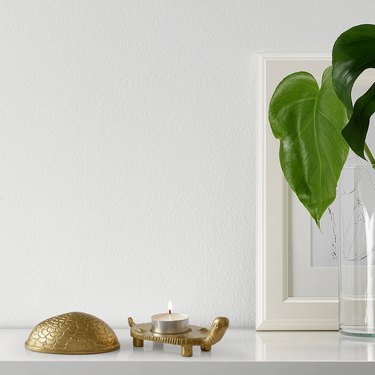 turtle-shaped holder with tea light candle next to framed art and plant