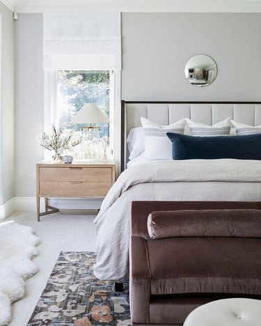 Modern bedroom with a taupe velvet sofa at the bottom of the bed