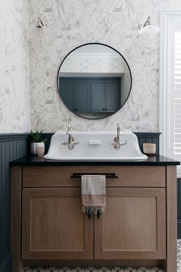 gray bathroom with patterned wallpaper and beadboard wainscoting