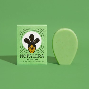 green soap box with green soap next to it on green background