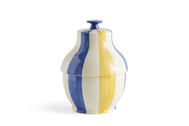 A white, blue, and yellow striped cookie jar with a lid over a white background.