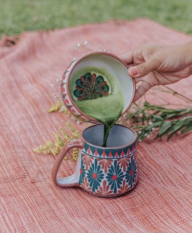 person pouring drink into patterned mug