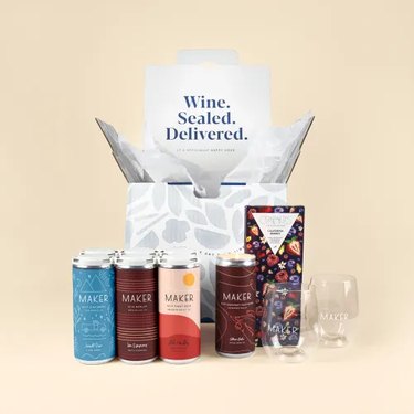 box that reads "wine sealed delivered" and cans of wine next to chocolate