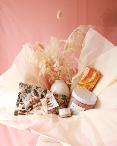 items in pink tissue paper, including dried florals and bath salts