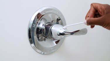 A woman swabbing a shower handle