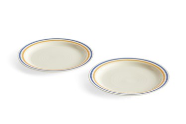 Two beige dinner plates with blue and yellow striped rims over a white background.