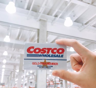 A person holding a Costco membership card in a Costco warehouse.