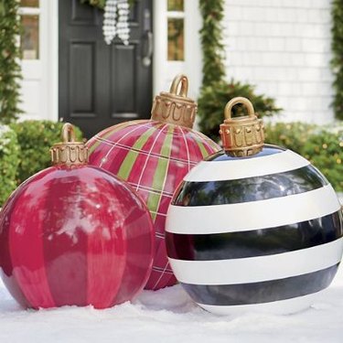 Three blow-up yard ornaments in snow in front of a house with a black door.