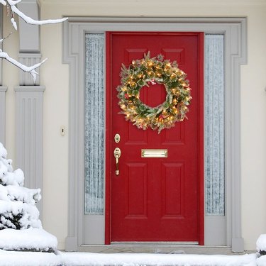 A red front door with a holiday wreath on it
