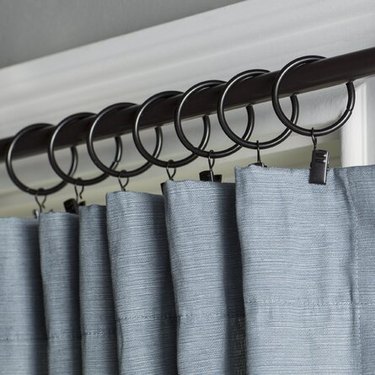 Bronze curtain rings holding up a blue curtain