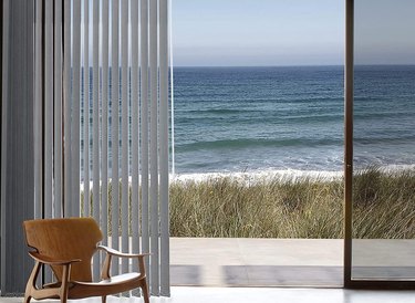 Open vertical blinds and sliding glass door, view of beach, ocean