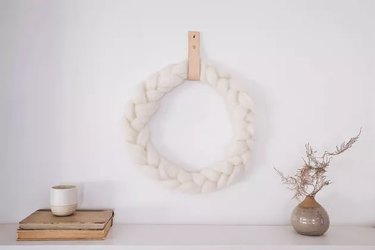 braided wool wreath hanging on a white wall