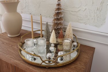 Mini mercury glass ball ornaments scattered around mirrored tray