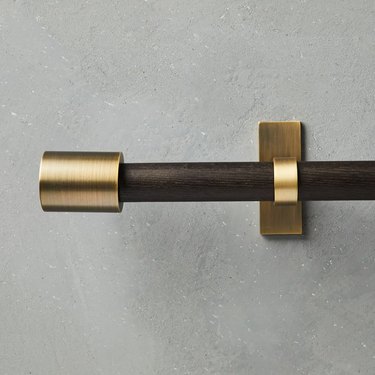 A curtain rod with a brass end cap and bracket
