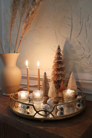 DIY mirrored tray holiday centerpiece with candles lit, bottle brush trees and ornaments