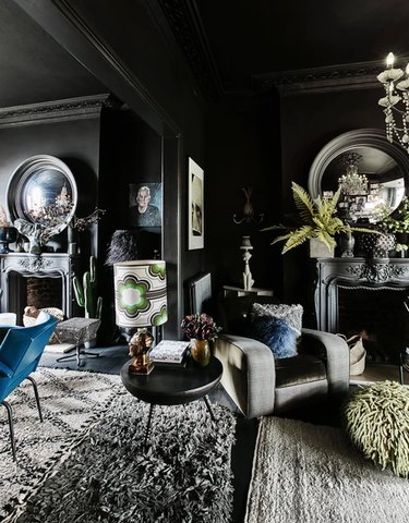 black living room with tall ceilings and large round mirrors