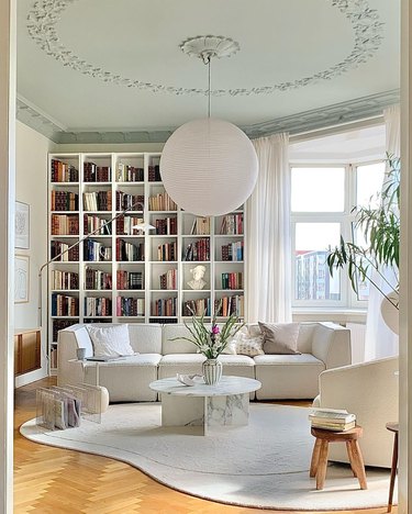 A white room with a white couch, white coffee table, and white bookshelf in the background.