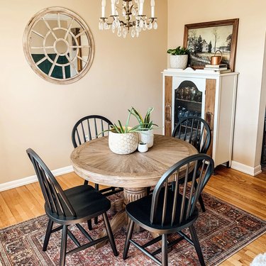 Dining room table with black chairs and potted plants.