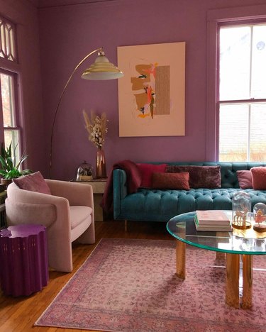 Living room with orchid purple walls, pink Persian rug, teal sofa and pink side chair.