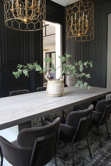 Dining room table with oversized pottery and large green branches.