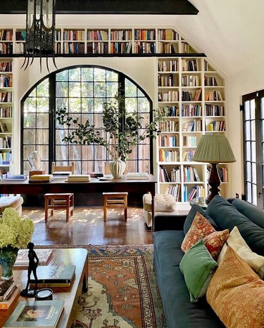 A living room space with white walls and a bookshelf built into the wall that goes over the doorway.