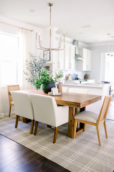 Bright dining room with wood table and greenery.