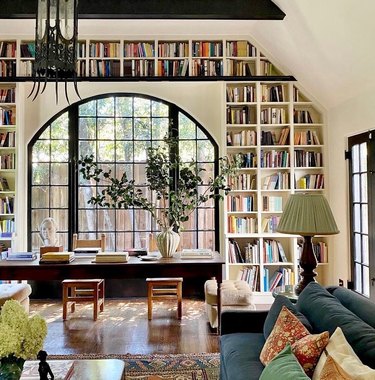 A living room space with white walls and a bookshelf built into the wall that goes over the doorway.