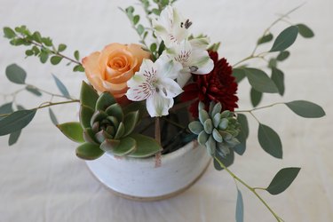 Orange rose, burgundy mum and white Lillies added to succulent centerpiece