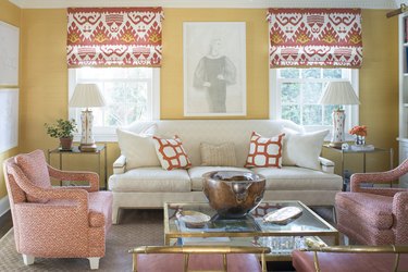 Living room with yellow walls and ikat print coral, yellow and white window treatments.