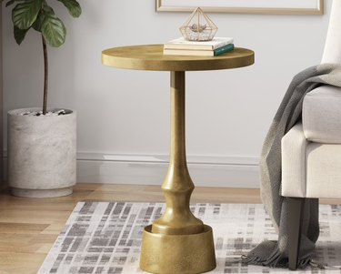 Brass end table, plant, rug.