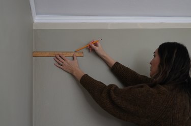 Marking measurements on wall with pencil and ruler