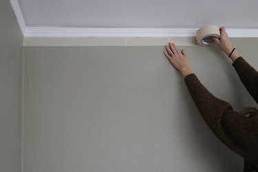 Attaching white painter's tape along top edge of wall
