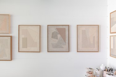 Canvases with neutral geometric shapes hanging on a white wall
