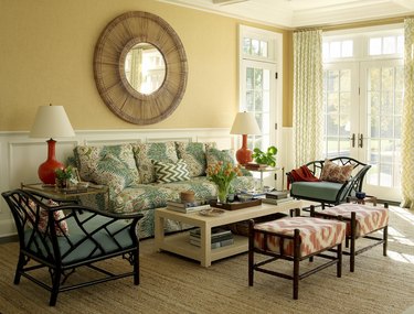 Living room with butter yellow walls, green and white curtains, turquoise print sofa, and coral print ottomans.