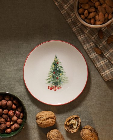 an overhead photo of a plate with a christmas tree design near snacks and a plaid napkin