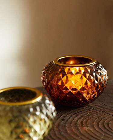 two glass tealight holders, a green one out of focus and another amber one nearby