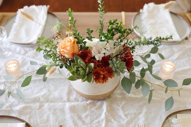 DIY succulent floral centerpiece on table with place settings and candles