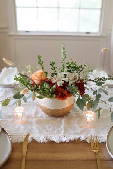 Succulent floral centerpiece on table with candles and place settings