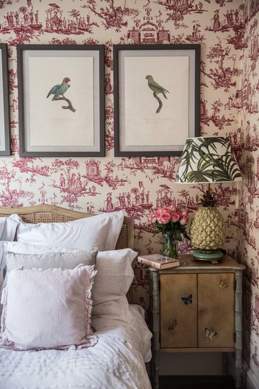 bedroom with pink and white toile wallpaper and ruffle pillows