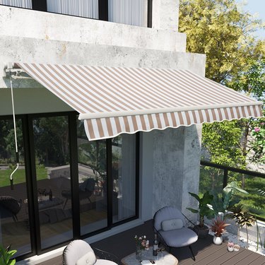 A tan and white striped retractable exterior awning is hung over a patio door