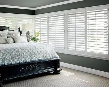 A bedroom with white shutters across two walls