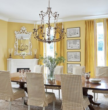 A classic living room with a hint of whimsy, with yellow walls and curtains, wrought iron accents and plaid slipcovered chairs.