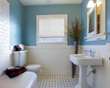 A vintage bathroom with black and white flooring, a blue wall, and a honeycomb Redi Shade Simple fit