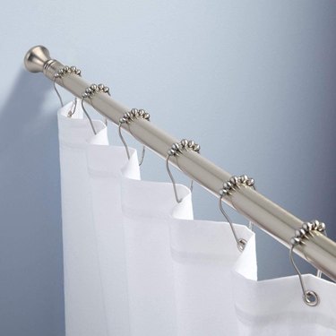 A tension rod holding a white curtain