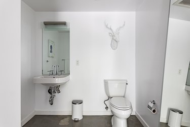 Minimalist bathroom with a full-length mirror and a white deer animal head sculpture
