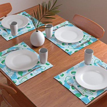Four Hidden Valley Ranch placemats on a wooden table with white plates and white cups.
