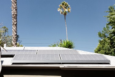 Solar panels on the roof of a home with palm trees in the background